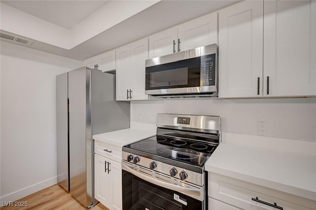 8412 Mulcahy Ave, Las Vegas, NV 89145 - kitchen featuring appliances with stainless steel finishes, light countertops, white cabinetry, light wood-style flooring, and baseboards
