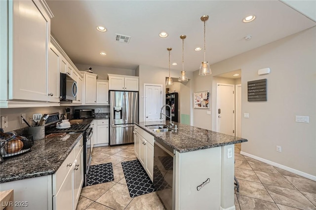 kitchen with stainless steel appliances, a sink, recessed lighting, an island with sink, and dark stone countertops
