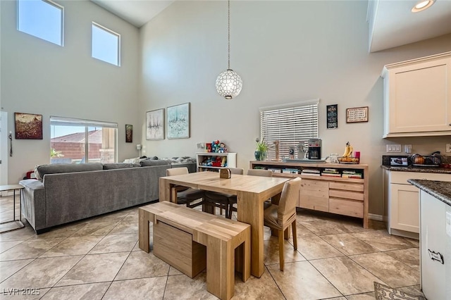 dining area with a towering ceiling, plenty of natural light, and light tile patterned flooring
