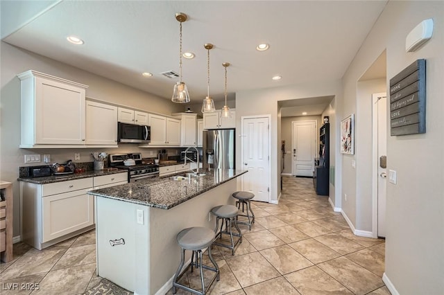 kitchen featuring appliances with stainless steel finishes, a sink, baseboards, white cabinetry, and recessed lighting