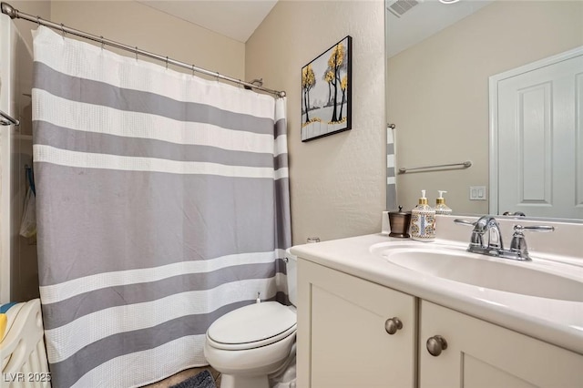 bathroom featuring toilet, vanity, and a shower with curtain