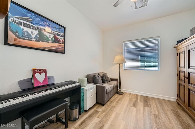 living area with a ceiling fan, light wood finished floors, and baseboards