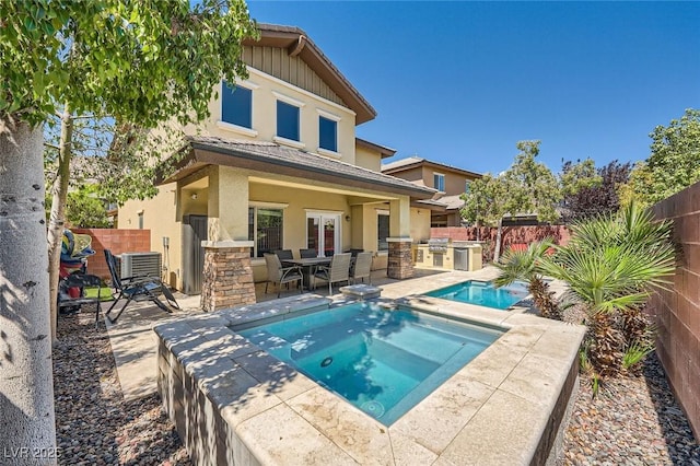 back of house with an outdoor kitchen, an in-ground hot tub, central AC, a fenced backyard, and a patio