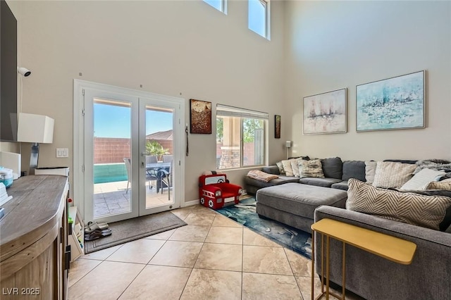 living area with french doors, a towering ceiling, and light tile patterned floors