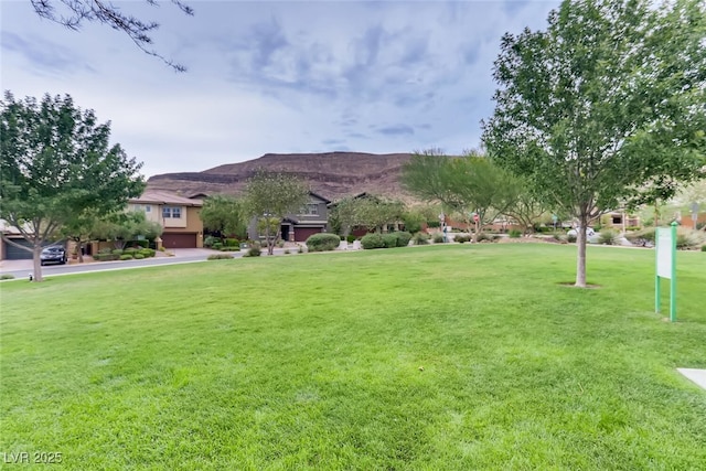 view of grassy yard with a mountain view and a garage
