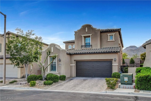 mediterranean / spanish home with stucco siding, a garage, a tiled roof, driveway, and a balcony