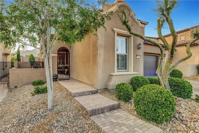 view of front facade featuring a garage, stucco siding, a gate, and a fenced front yard