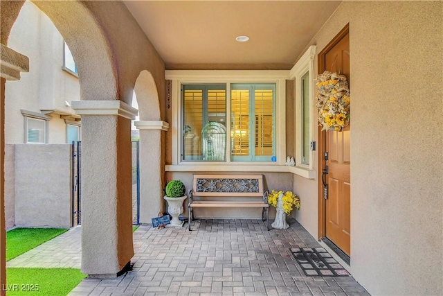 entrance to property with stucco siding and a gate