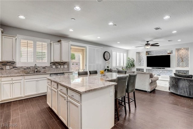 kitchen with a sink, a kitchen breakfast bar, a kitchen island, decorative backsplash, and recessed lighting
