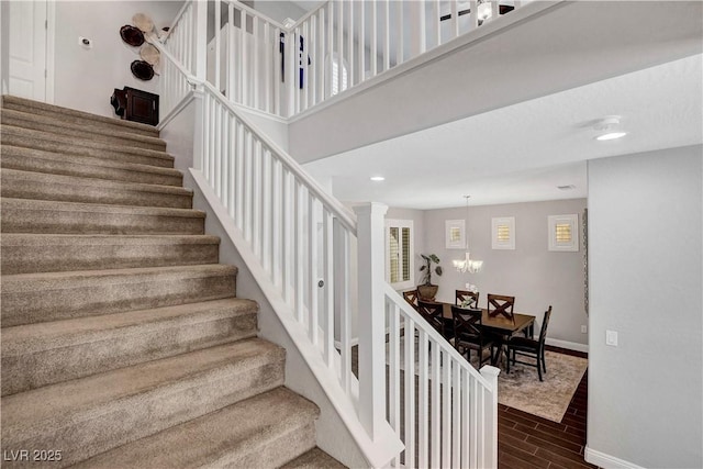 stairway featuring wood finished floors, baseboards, a chandelier, and recessed lighting