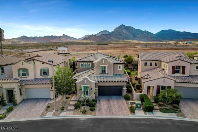 view of front of home featuring a garage, stucco siding, a mountain view, and driveway