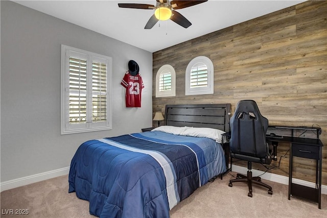 carpeted bedroom featuring baseboards, wood walls, and ceiling fan