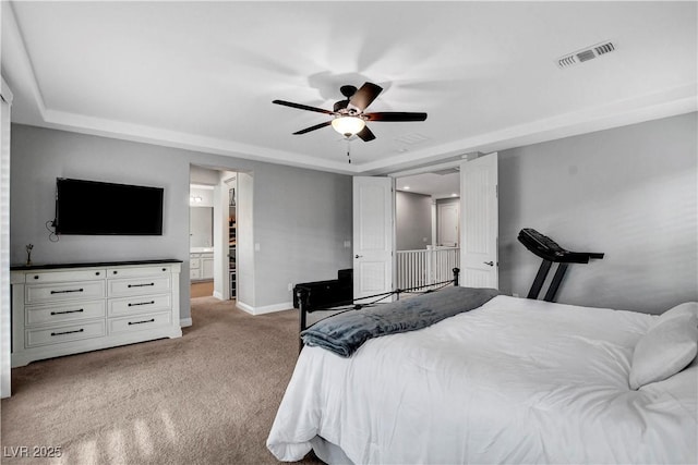 bedroom featuring baseboards, carpet flooring, a tray ceiling, and connected bathroom