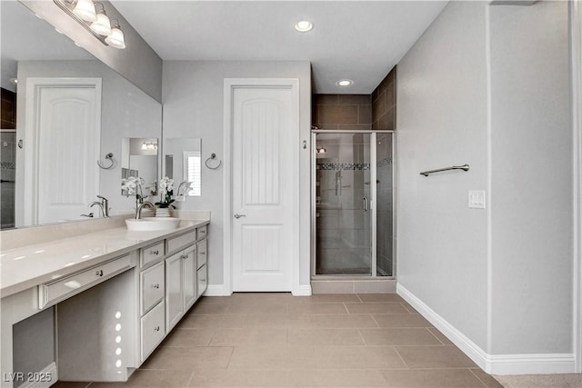 bathroom featuring baseboards, a shower stall, double vanity, recessed lighting, and tile patterned floors