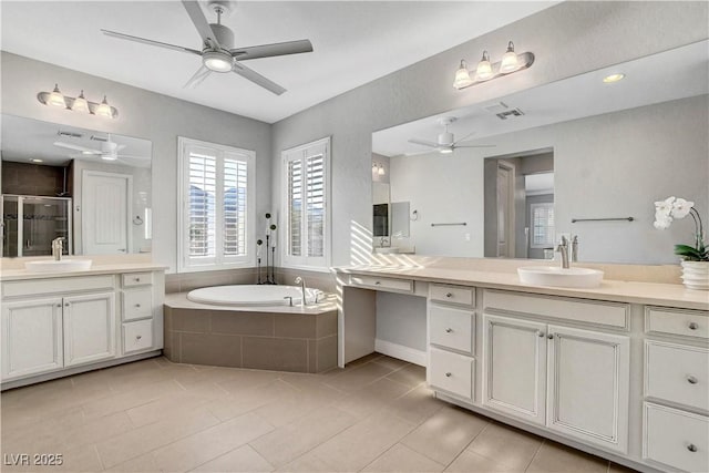 bathroom featuring a ceiling fan, plenty of natural light, tile patterned flooring, and a garden tub