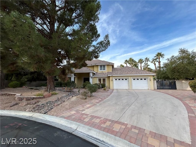view of front facade with driveway, an attached garage, fence, and stucco siding
