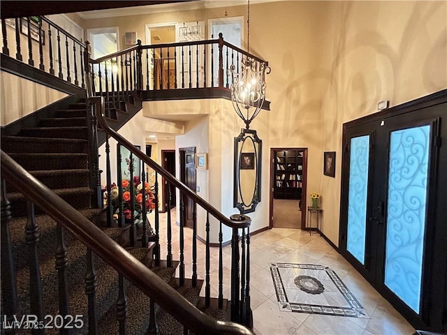 tiled foyer featuring baseboards, a towering ceiling, stairway, ornamental molding, and french doors