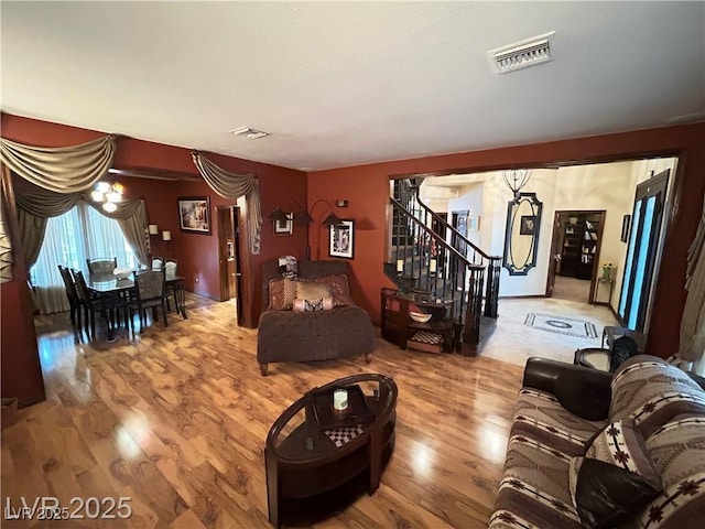 living area with wood finished floors, stairs, and a chandelier