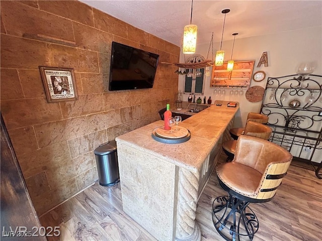 bar featuring wood finished floors, tile walls, and pendant lighting