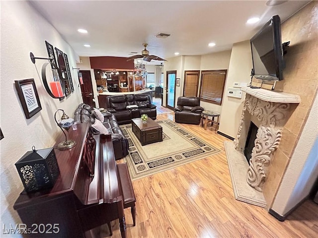 living area featuring light wood-type flooring, a ceiling fan, recessed lighting, and a premium fireplace
