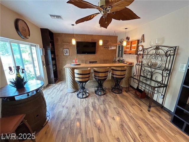 indoor bar with wood finished floors, pendant lighting, and ceiling fan