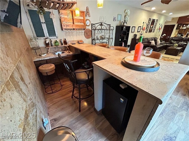 kitchen with wood finished floors, a kitchen breakfast bar, recessed lighting, and a peninsula