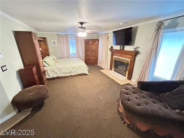 carpeted bedroom featuring ornamental molding, a fireplace with flush hearth, a ceiling fan, and baseboards