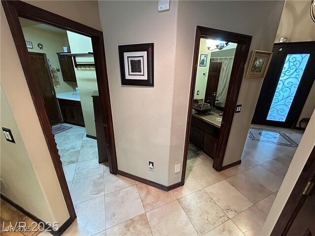 hall with baseboards and light tile patterned floors