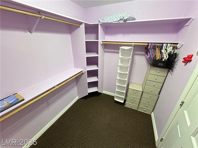 walk in closet featuring dark carpet