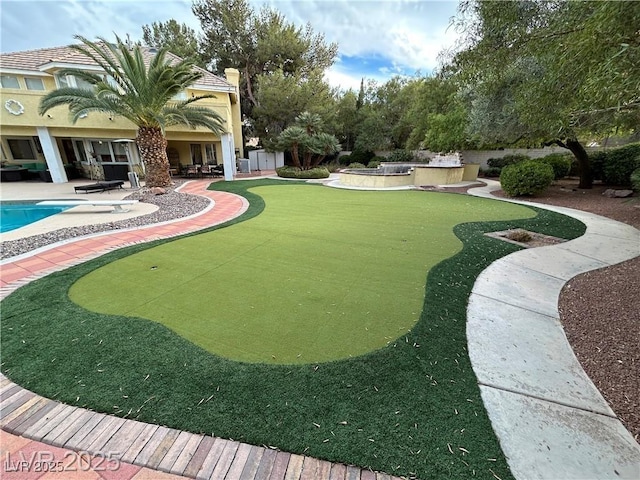 view of yard with a putting area, a patio, and an outdoor pool