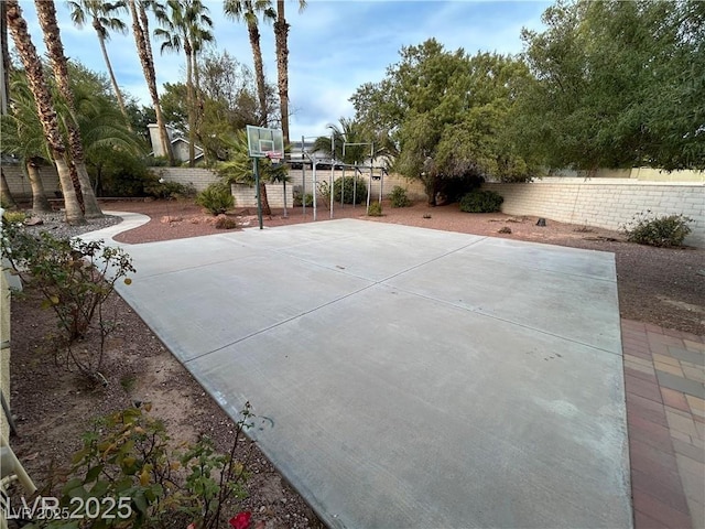 view of basketball court with basketball hoop and a fenced backyard