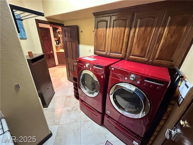 clothes washing area featuring separate washer and dryer, cabinet space, and light tile patterned floors