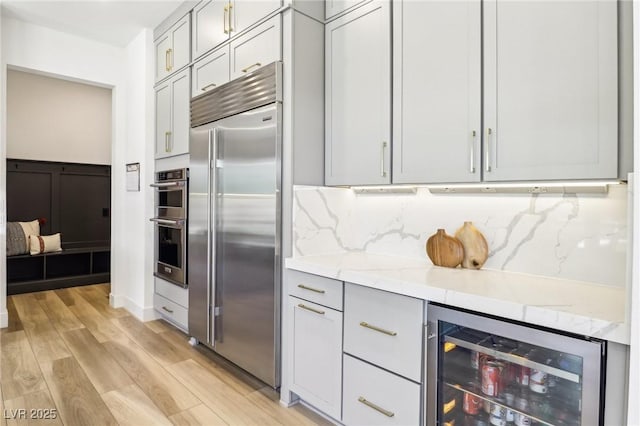 12155 Sage Thunder Ave, Las Vegas, NV 89138 - kitchen featuring built in refrigerator, beverage cooler, light wood-type flooring, decorative backsplash, and light stone counters