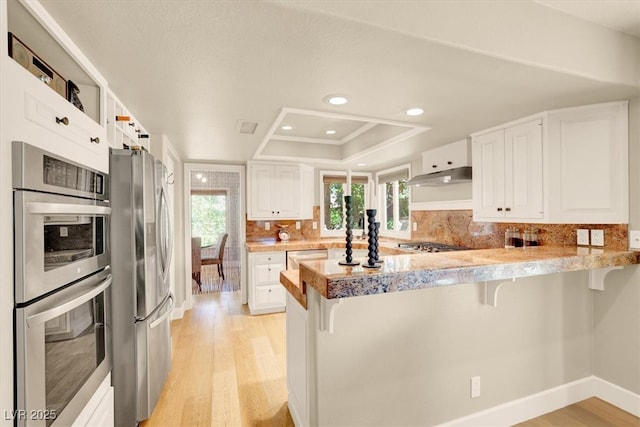 5142 Southern Hills Ln, Las Vegas, NV 89113 - kitchen with appliances with stainless steel finishes, a peninsula, a breakfast bar area, light wood-type flooring, and recessed lighting