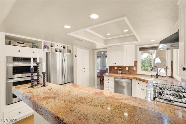 5142 Southern Hills Ln, Las Vegas, NV 89113 - kitchen featuring stainless steel appliances, a sink, a raised ceiling, white cabinetry, and light stone countertops