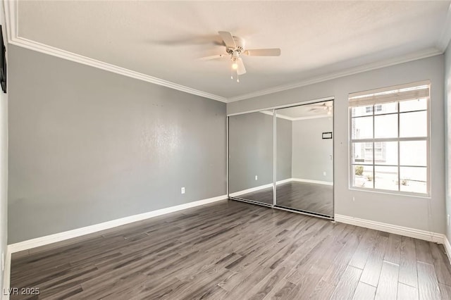 unfurnished bedroom with ornamental molding, wood finished floors, baseboards, a closet, and a ceiling fan