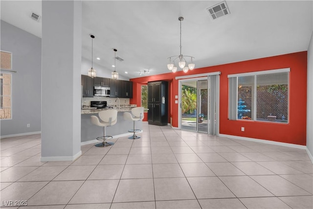 4644 Canna Dr, Las Vegas, NV 89122 - kitchen featuring stainless steel microwave, a kitchen breakfast bar, a chandelier, light tile patterned flooring, and baseboards