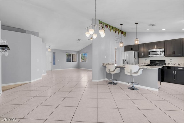 4644 Canna Dr, Las Vegas, NV 89122 - kitchen with stainless steel appliances, open floor plan, light tile patterned floors, a breakfast bar, and pendant lighting