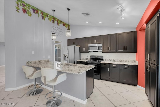 4644 Canna Dr, Las Vegas, NV 89122 - kitchen featuring stainless steel appliances, vaulted ceiling, a peninsula, light tile patterned floors, and a breakfast bar area