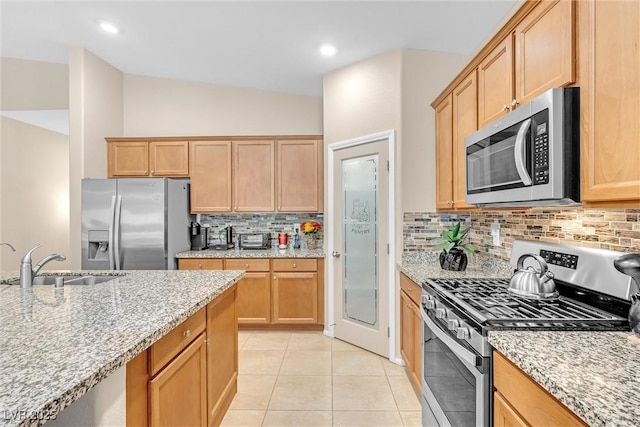 kitchen with appliances with stainless steel finishes, a sink, light stone countertops, decorative backsplash, and recessed lighting