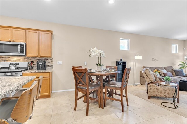 dining space featuring healthy amount of natural light, light tile patterned floors, and baseboards
