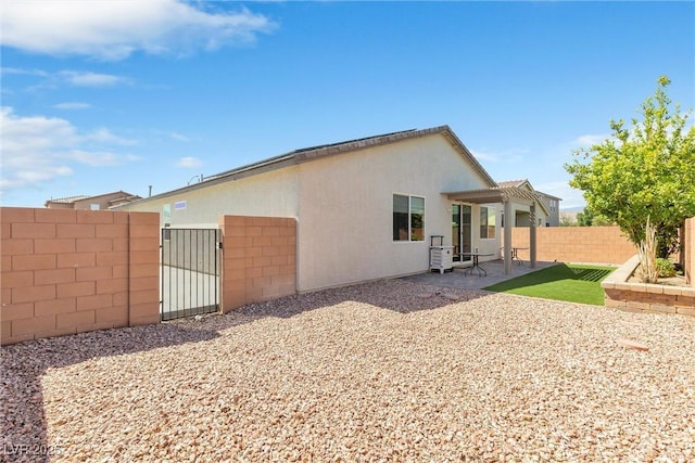 rear view of house with a patio, a gate, stucco siding, and a pergola