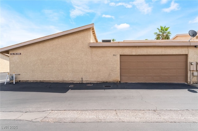 2261 Tall Pine Dr, Las Vegas, NV 89108 - view of home's exterior featuring stucco siding, an attached garage, and asphalt driveway