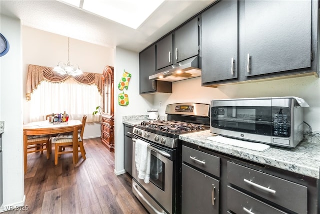 2261 Tall Pine Dr, Las Vegas, NV 89108 - kitchen featuring stainless steel appliances, under cabinet range hood, a chandelier, dark wood-style flooring, and dark cabinetry