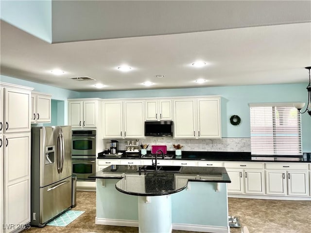 kitchen featuring appliances with stainless steel finishes, a sink, decorative backsplash, a center island with sink, and recessed lighting