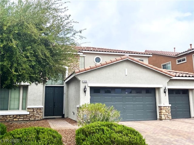 view of front of property featuring stone siding, an attached garage, stucco siding, and decorative driveway