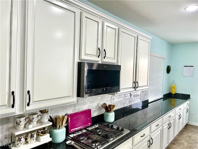kitchen featuring tasteful backsplash, stainless steel gas cooktop, dark stone counters, and white cabinetry
