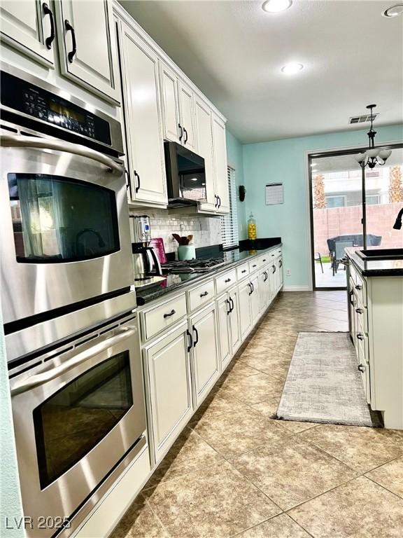 kitchen featuring stainless steel double oven, dark countertops, backsplash, light tile patterned floors, and recessed lighting