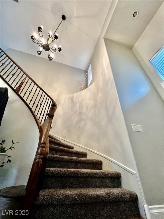 stairs with a chandelier, a high ceiling, and baseboards