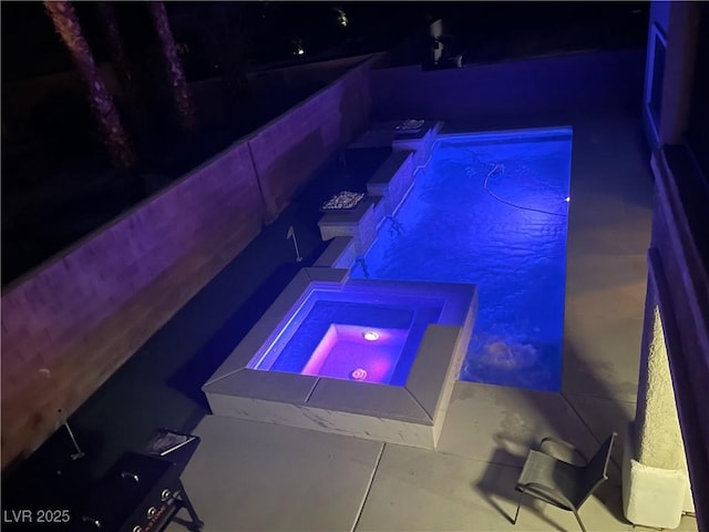 pool at night featuring an in-ground hot tub and an outdoor pool